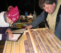 A scientist examining drill core and another scientist taking notes.