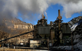 a power plant with two smoke stacks nestled between two mountains