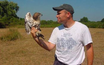 Photo of Professor James Hewlett with a juvenile male red-tailed hawk.