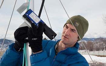 a researcher setting up the equipment to measure how much snow and the crystal type.