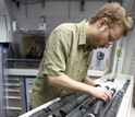 Photo of geologist Chad Broyles studying a rock core aboard the JOIDES Resolution.