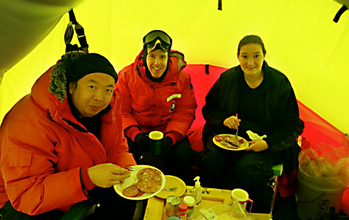 Three researchers share a meal in an Antarctic tent