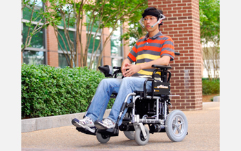 Photo of Xueliang Huo moving his tongue to direct the Tongue Drive System to move the wheelchair.