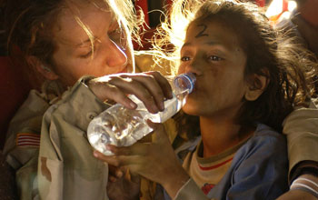 Photo of a US woman soldier giving water to drink to a girl.