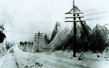 Photo of a snow-covered road and telephone wires sagging under a heavy burden of snow.