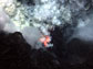 Photo of an explosion of ash and rock at the West Mata Volcano with molten lava glowing below.