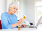 a woman using a laptop looking at a pill bottle
