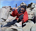 Person on mountain with rock hammer. Click for credit.