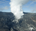 The glacier is covered with volcanic ash, and steam rises as glacial meltwater meets lava flow.