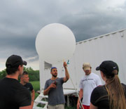 A research team of four men and one woman prepare to launch a weather balloon.