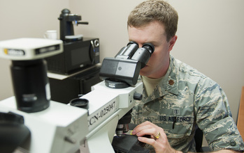 Air Force Major Michael McFall looks through a microscope