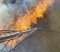 An experimental grass fire spreads under a meteorological tower.