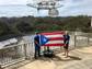 Arecibo staff hold up a Puerto Rico flag with the telescope array in the background.