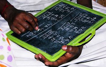 hands of a girl doing math problems on slate