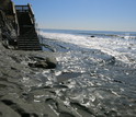 Exposed bedrock platform at beach access staircase, where large waves swept away the sand.