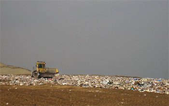 A piece of heavy equipment pushes trash in a landfill.