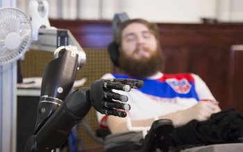 A man manipulates a robotic arm via a computer chip in his brain.