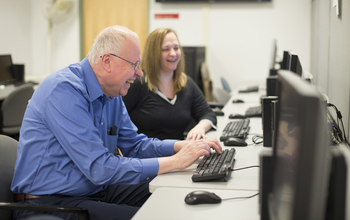 Sociologist Andrew Beveridge with a student at a computer