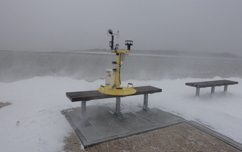 A Weather Pod on a bench next to water and snow