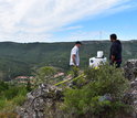 A scanning LIDAR measures wind velocity and turbulence. A wind turbine is in the background.