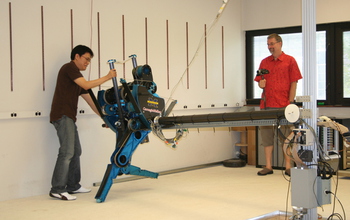 Two people and a robot with lateral support boom.