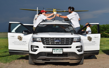 Researchers load instrumentation onto a tracker vehicle before a drone's takeoff.