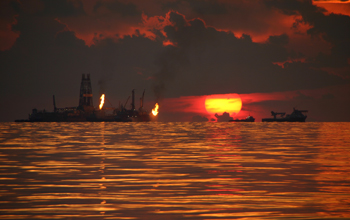 Sun sets over the Gulf of Mexico while drillships flare natural gass on surface