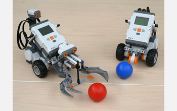 Photo of robots programmed by students that are handling balls.