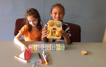 two girls with crayons, a robot and cubes