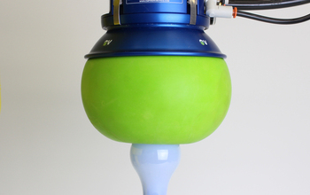 A spherical robotic hand filled with granular material that is gripping a lightbulb