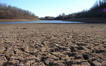 cracked soil near a river in an area affected by drought