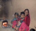 a Indian woman and her two children with a dung or wood fuel cooking stove.