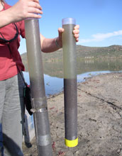 Photo of a scientist holding two sediment cores from South Africa's Lake Verlorenvlei.