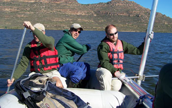 Photo of Brian Chase holding a core, Christiann King paddling and Curt Stager steering.