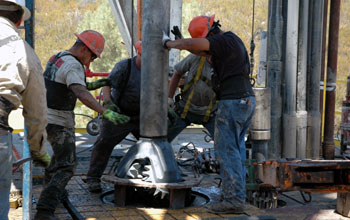 Rig hands attach a new drill bit to the drill pipe