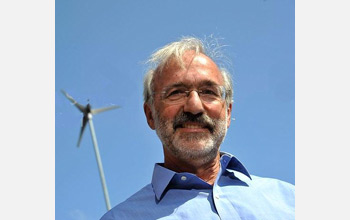 Photo of Michael Caramanis under a small wind generator.