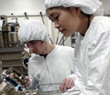 Photo of Ting Liu explaining the use of molecular beam epitaxy to undergraduate Kirk Pirlo.