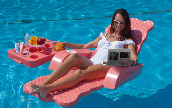 a woman in a bathing suit floating in a pool viewing a electrofluidic display technology.