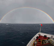 View of ocean horizon and rainbow from bow of research vessel.