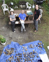 Photo showing bones of many large mammals on a groundcloth and three scientists.