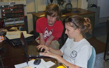 Scientists recording data in a lab aboard the research vessel Thompson during a project cruise.