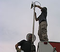 Two men work on a communications antenna.
