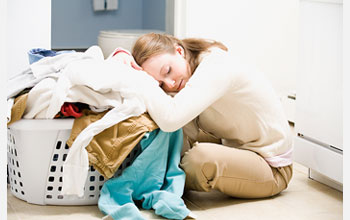 Photo of woman resting her head on basket of laundry.