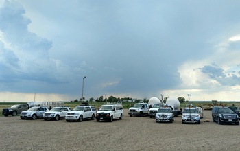 multiple vehicles in an open field under a daunting sky