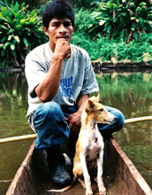 a Mayangna hunter and his dog resting in a dugout canoe.