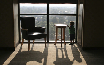 Child looking outside the window from a high floor