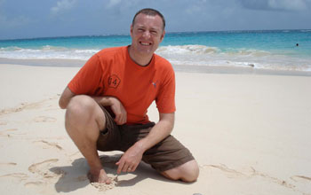 Photo of Rob Condon in Bermuda with Portuguese Man-o-War jelly washed up on beach.