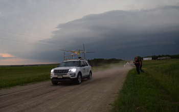 a vehicle traveling on a dirt road with a stormy sky
