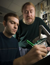 Photo of Richard Lenski and another researcher examining a Petri dish.