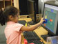 Photo of a girl using a computer to match shapes to build pictures.